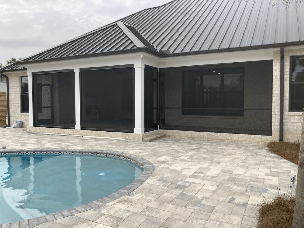 Piscina y deck de piedra clara junto a una casa con screen en Florida, construidos por Marblu