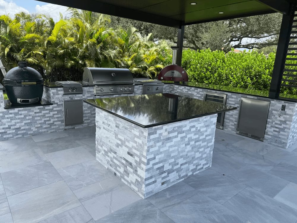 Isla de cocina exterior terminada en piedra natural en un patio de Marblu