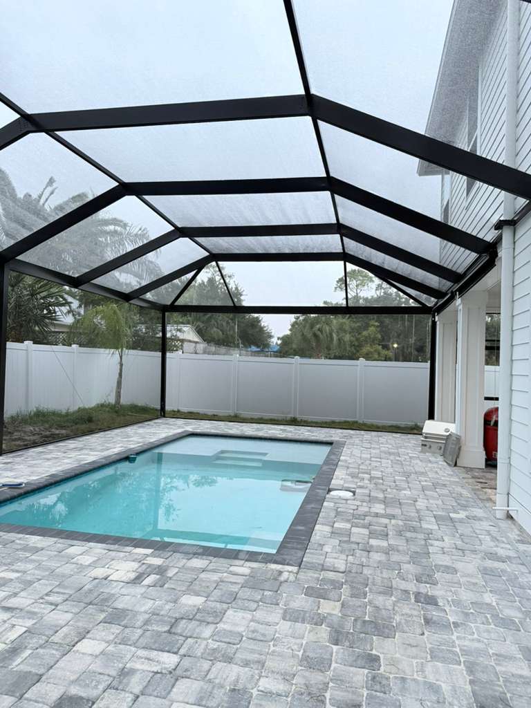 A Marblu-built panoramic screen enclosure over a Florida patio, corner view against the sky
