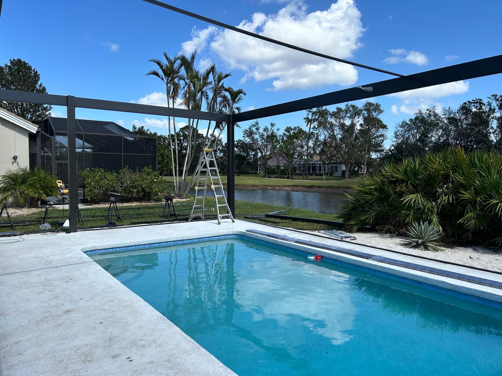 Estructura de enclosure siendo montada sobre un deck de piscina junto al lago