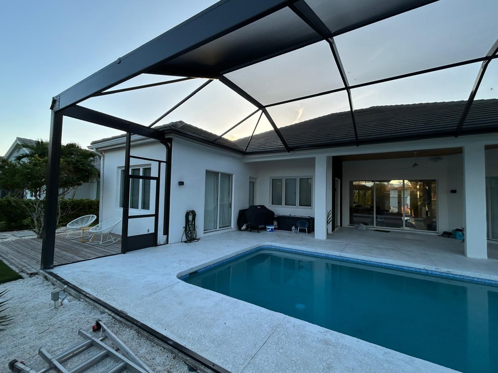 Enclosure contemporáneo de marco negro sobre un deck de travertino al atardecer, Jacksonville